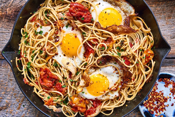 Spaghetti with fried duck eggs, tomatoes & shallots