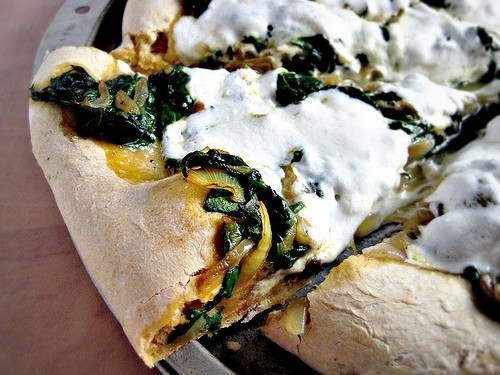 Spinach and onion curry pizza on a pumpkin pizza dough crust 