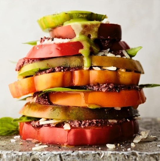 Stacked tomato salad with black olive tapenade, Garrotxa cheese, and sweet basil dressing 
