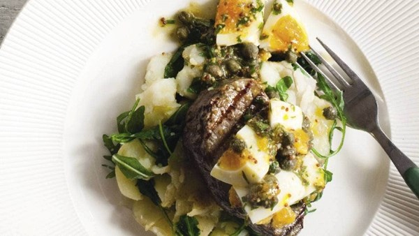 Steaks with egg, caper and mustard dressing on crushed potatoes and rocket