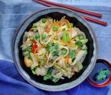 Stir-fried flat rice noodles with omelette, leeks, peas, carrot and chilli