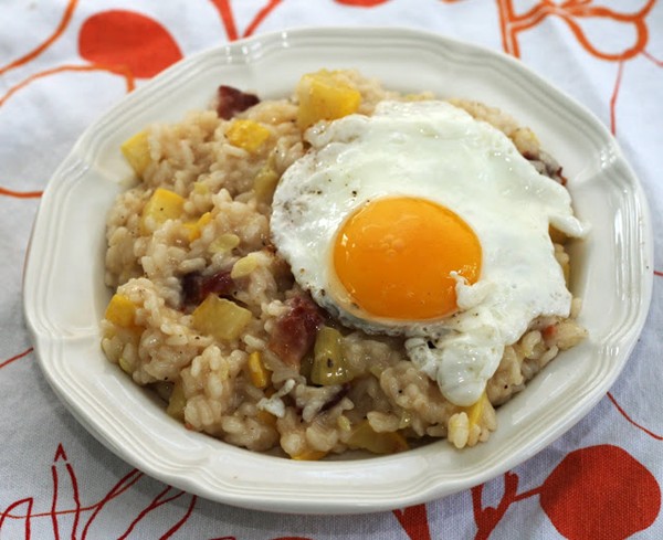 Sunny-side up egg topped crookneck squash risotto with bacon