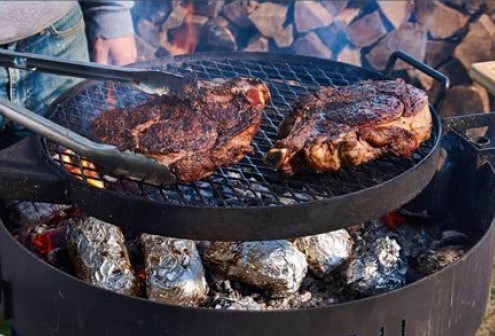 Thick-cut rib steaks with ember-baked potatoes