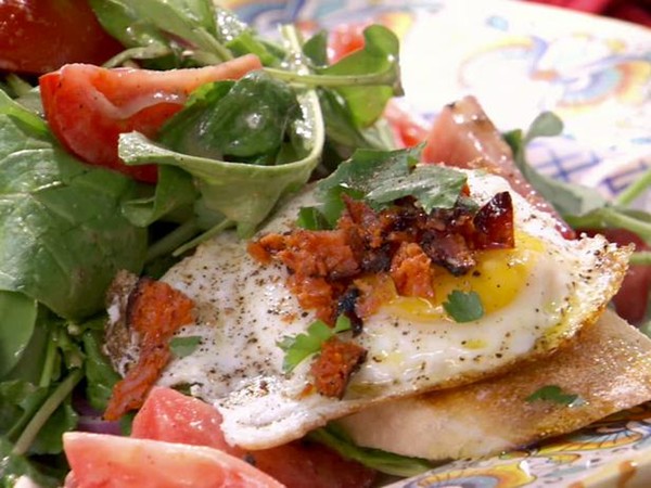 Tomato, red onion, and arugula salad with fried egg and chorizo