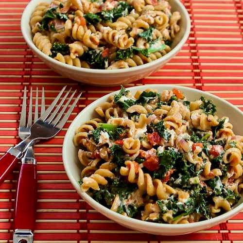 Vegetarian whole wheat pasta with fried kale, tomato sauce, and goat cheese