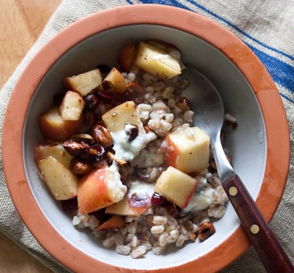 Warm farro breakfast bowl with apples, cranberries, and hazelnuts