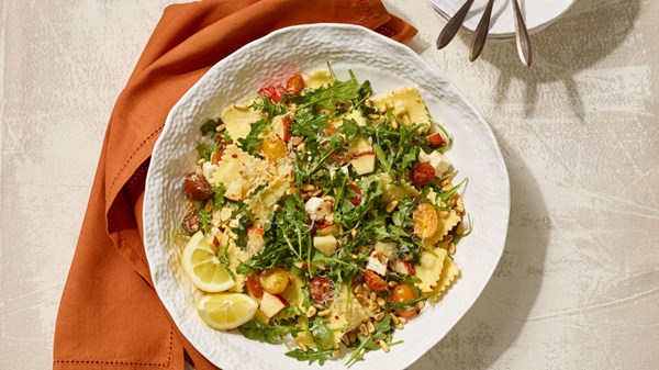Warm ravioli salad with marinated cheese, apple, and tomato