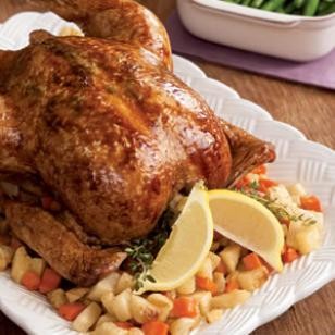 Whole roasted lemon-herb chicken on a bed of vegetables